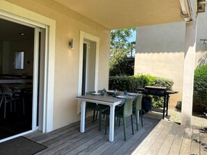 Une terrasse avec une table et des chaises, un barbecue et une vue sur le jardin.