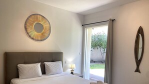 A hotel room with a large bed, a round mirror, and a view of the outdoors. - T3 face à la Mer by Pinarello Villa Services (Sainte-Lucie de Porto-Vecchio)