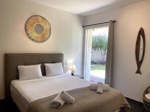 A hotel room with a large bed, a round mirror, and a view of the outdoors. - T3 face à la Mer by Pinarello Villa Services (Sainte-Lucie de Porto-Vecchio)