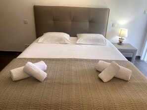 Une chambre d’hôtel avec un grand lit, deux oreillers, une lampe de chevet et deux serviettes sur le lit.
