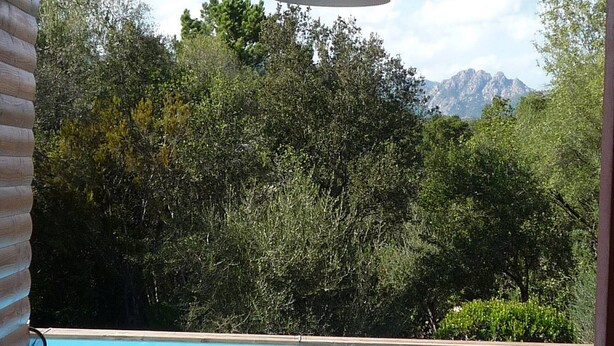 An outdoor pool area with wooden deck seating and a view of a mountain range.