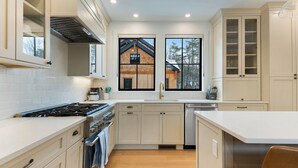 A modern kitchen with white cabinetry, a stove, oven, and a dishwasher. - Brand NEW Ski-in/Ski-out retreat at Cranmore Mt.! (North Conway)