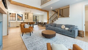 A spacious living area with a sofa, coffee table, and a staircase leading to an upper floor. - Brand NEW Ski-in/Ski-out retreat at Cranmore Mt.! (North Conway)
