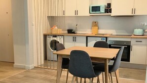 Eine moderne Küche mit weißen Schränken, einem Holzespeisetisch und einer Pendelleuchte.