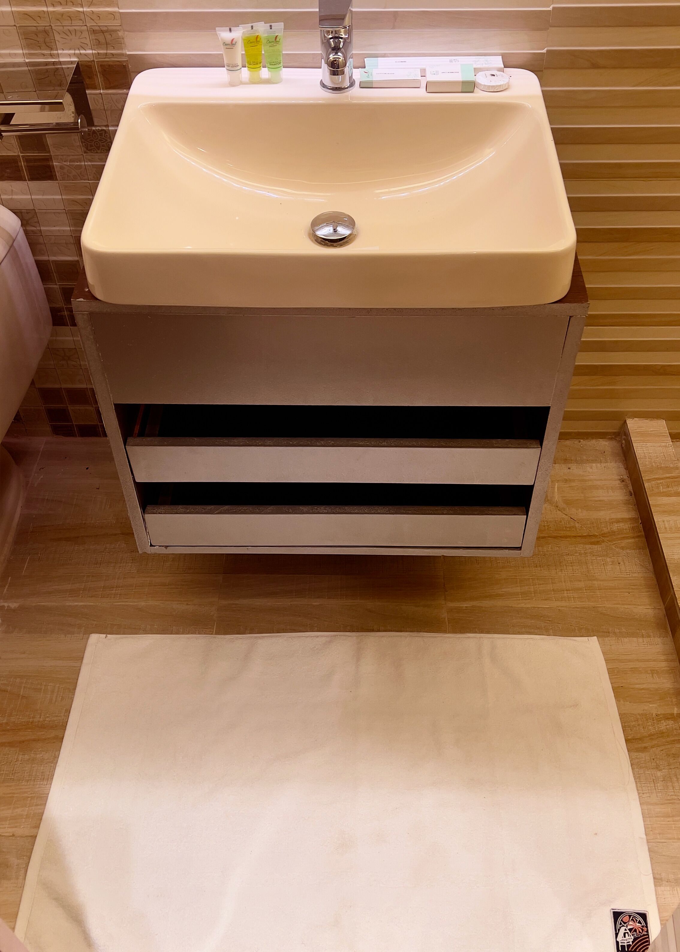 A bathroom with a beige sink, a mirror, and toiletries on the countertop.