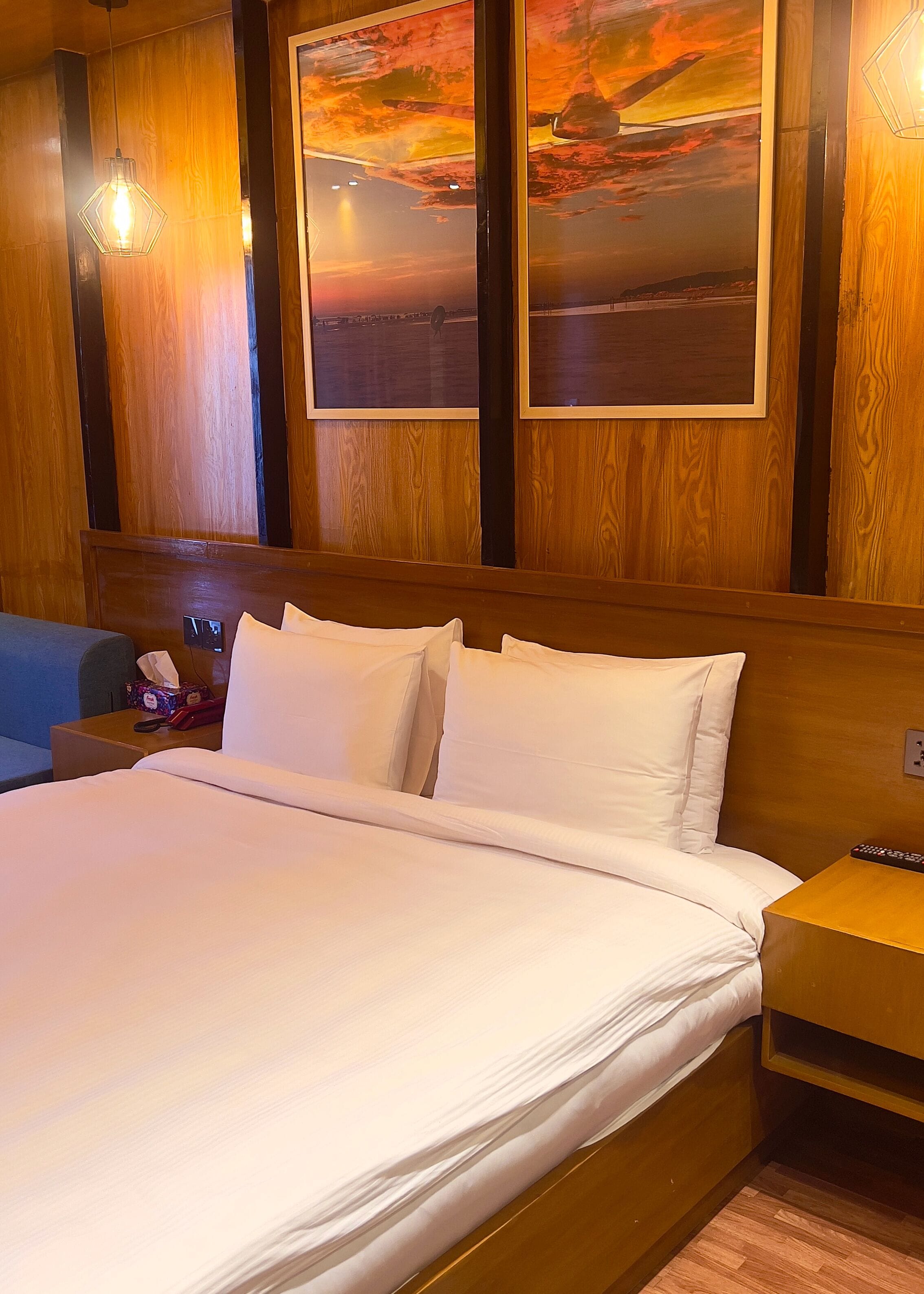 A hotel room with a large bed, wooden headboard, and a nightstand with a lamp.