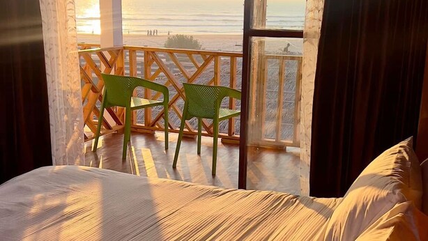 A bedroom with a bed, a view of the beach, and a wooden ceiling. - TUPTUP - Resto & Resort (Cox's Bazar)