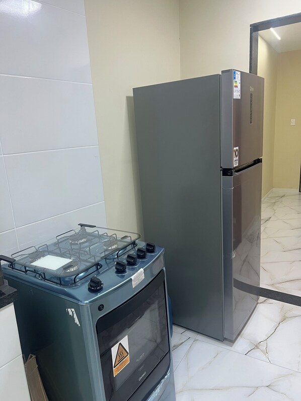 Una cocina con estufa a gas, refrigerador y paredes de azulejos.