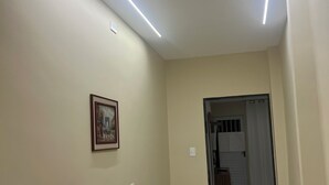 A hallway with a marble floor, a framed picture on the wall, and a door leading to a bathroom.