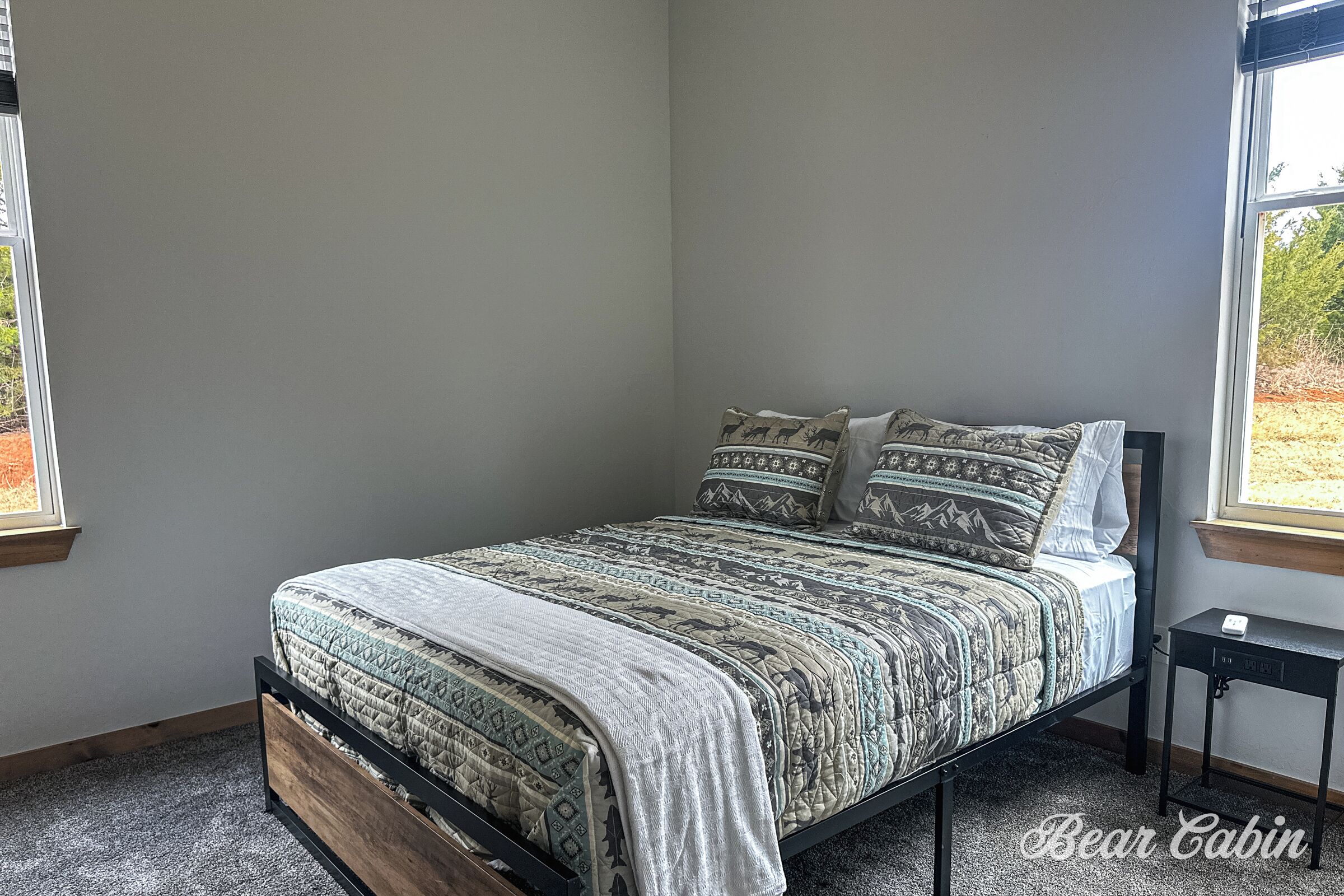 Una camera da letto con un letto, un comodino e due finestre.