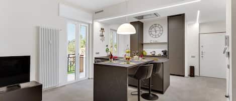 Una cocina moderna con una isla central, taburetes de bar, una mesa de comedor y un reloj grande en la pared.