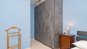 A bedroom with a wardrobe, a wooden ladder, a nightstand with a lamp, and a bed. - Luvi Maison - Affitti Brevi Italia (Terrazzano)