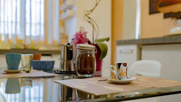 A kitchen counter with a coffee cup, a jar, and a vase with flowers. - Luvi Maison - Affitti Brevi Italia (Terrazzano)