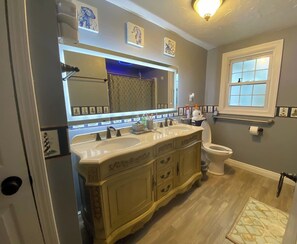 Une salle de bain avec un meuble-lavabo à deux vasques, des toilettes et une fenêtre.