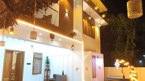 A two-story building with a covered outdoor area featuring a seating arrangement and a water feature. - Pepper Jazz Varkala : Double Room with Private Bathroom (Varkala)