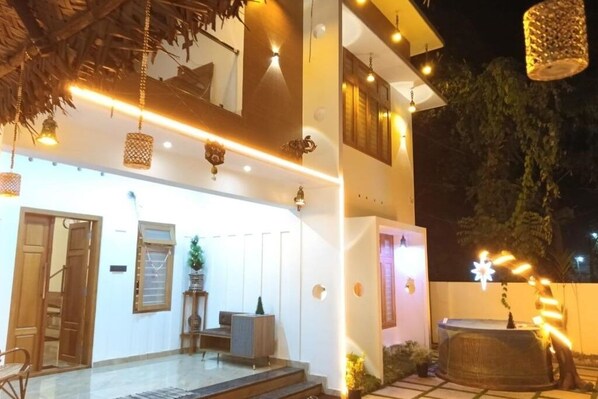 A two-story building with a covered outdoor area featuring a seating arrangement and a water feature.