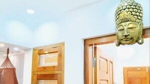 A room with a wooden door, a hanging woven light fixture, and a Buddha head sculpture. - Pepper Jazz Varkala : Double Room with Private Bathroom (Varkala)