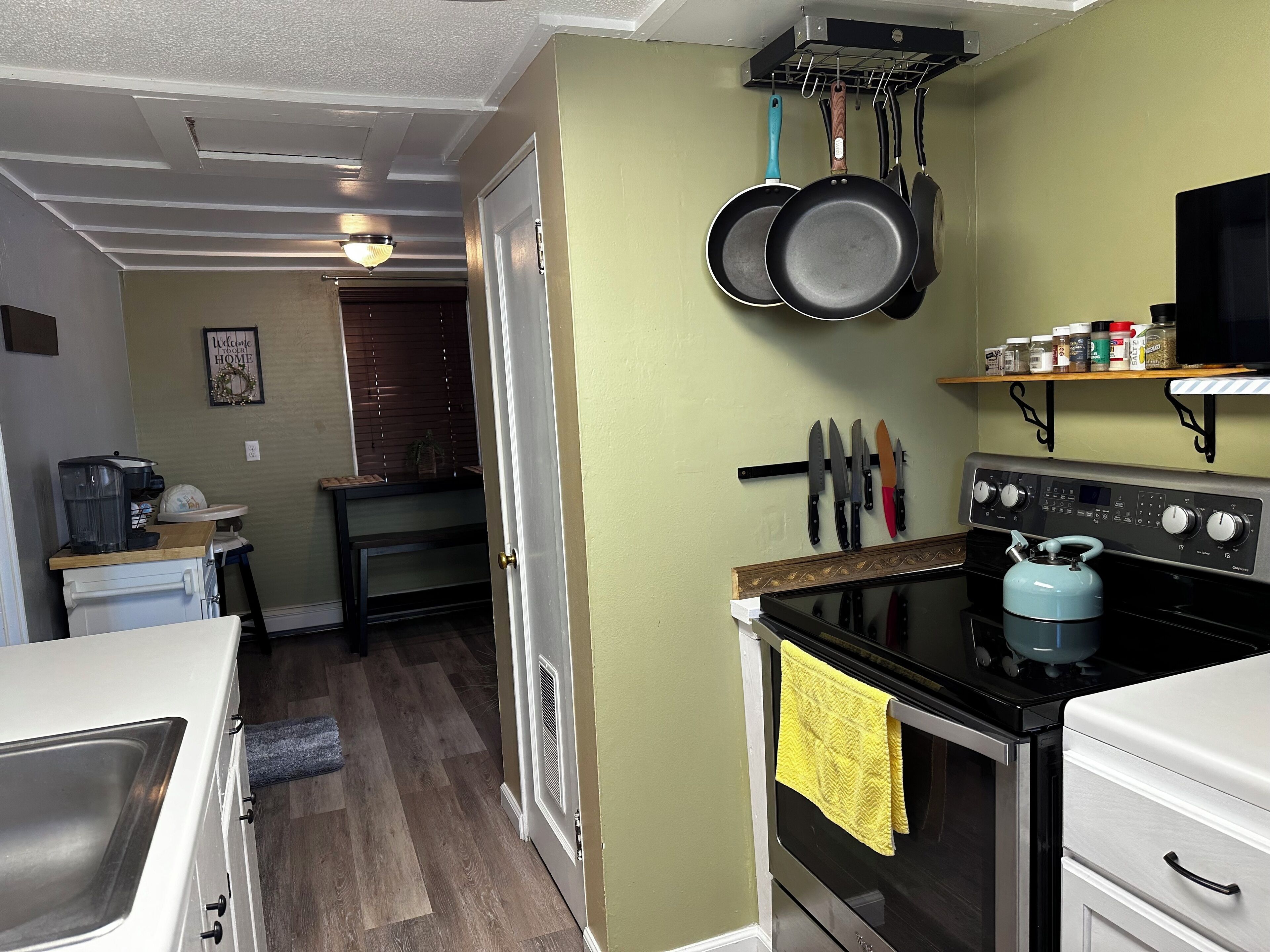 A compact kitchen with a stove, oven, and hanging pots.