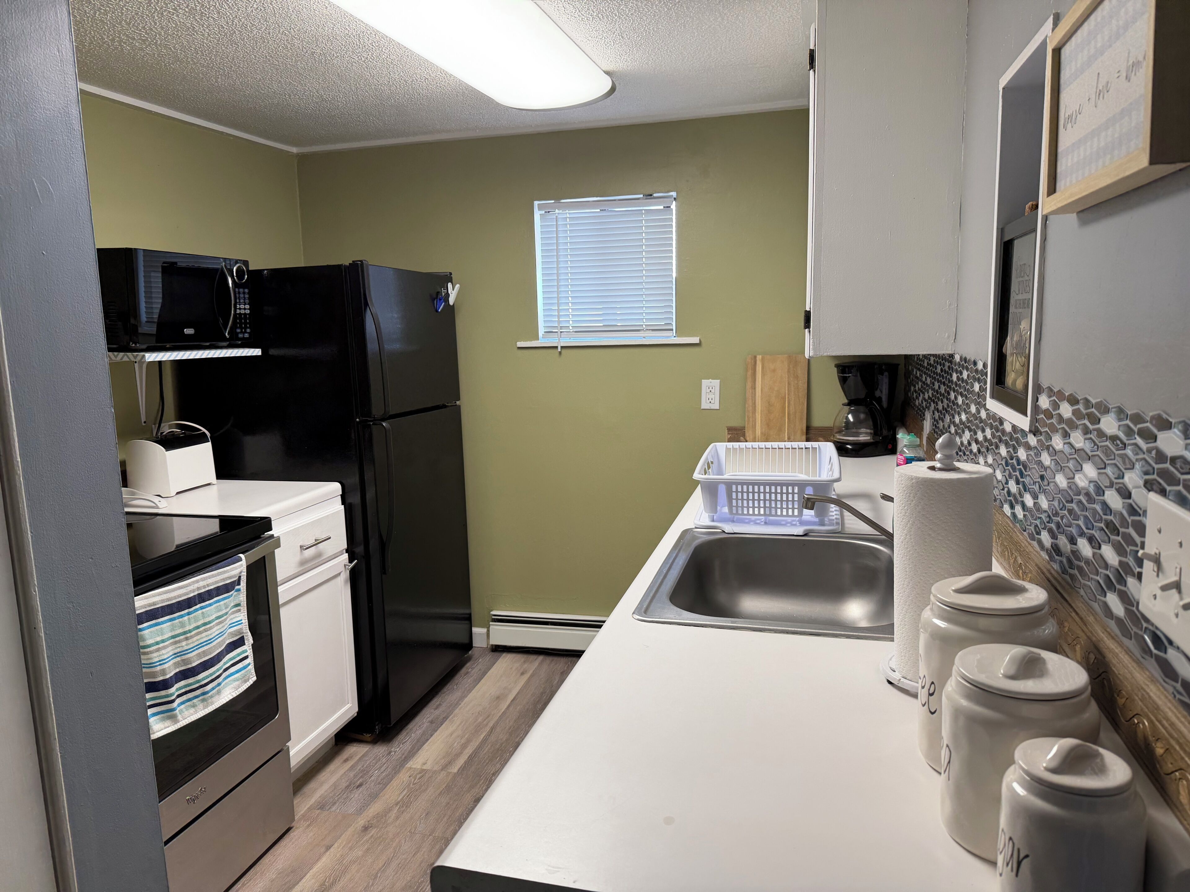Una cocina compacta equipada con refrigerador, microondas y lavavajillas.