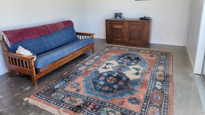 A room with a blue sofa, a wooden cabinet, and a patterned rug. - Vineyard accommodation close to Renwick. Quiet apartment surrounded by vines. (Hawkesbury)