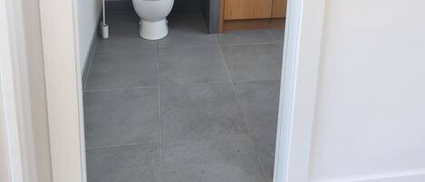 Een moderne badkamer met toilet, wastafel en spiegel.