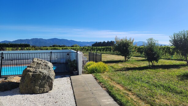 A modern building with a pool, surrounded by a vineyard and a clear blue sky. - Vineyard accommodation close to Renwick. Quiet apartment surrounded by vines. (Hawkesbury)