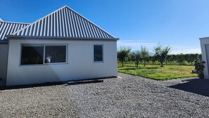 A modern building with a sloped metal roof and a gravel driveway. - Vineyard accommodation close to Renwick. Quiet apartment surrounded by vines. (Hawkesbury)