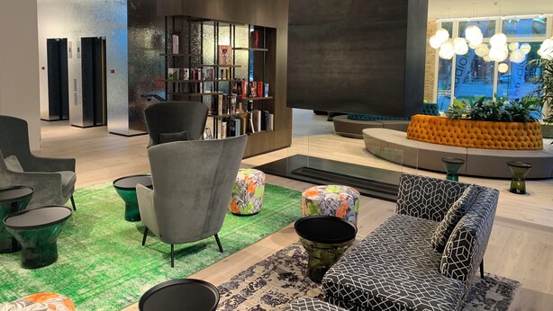 Un vestíbulo moderno con una zona de estar central, una estantería y un ventanal con vistas al exterior.