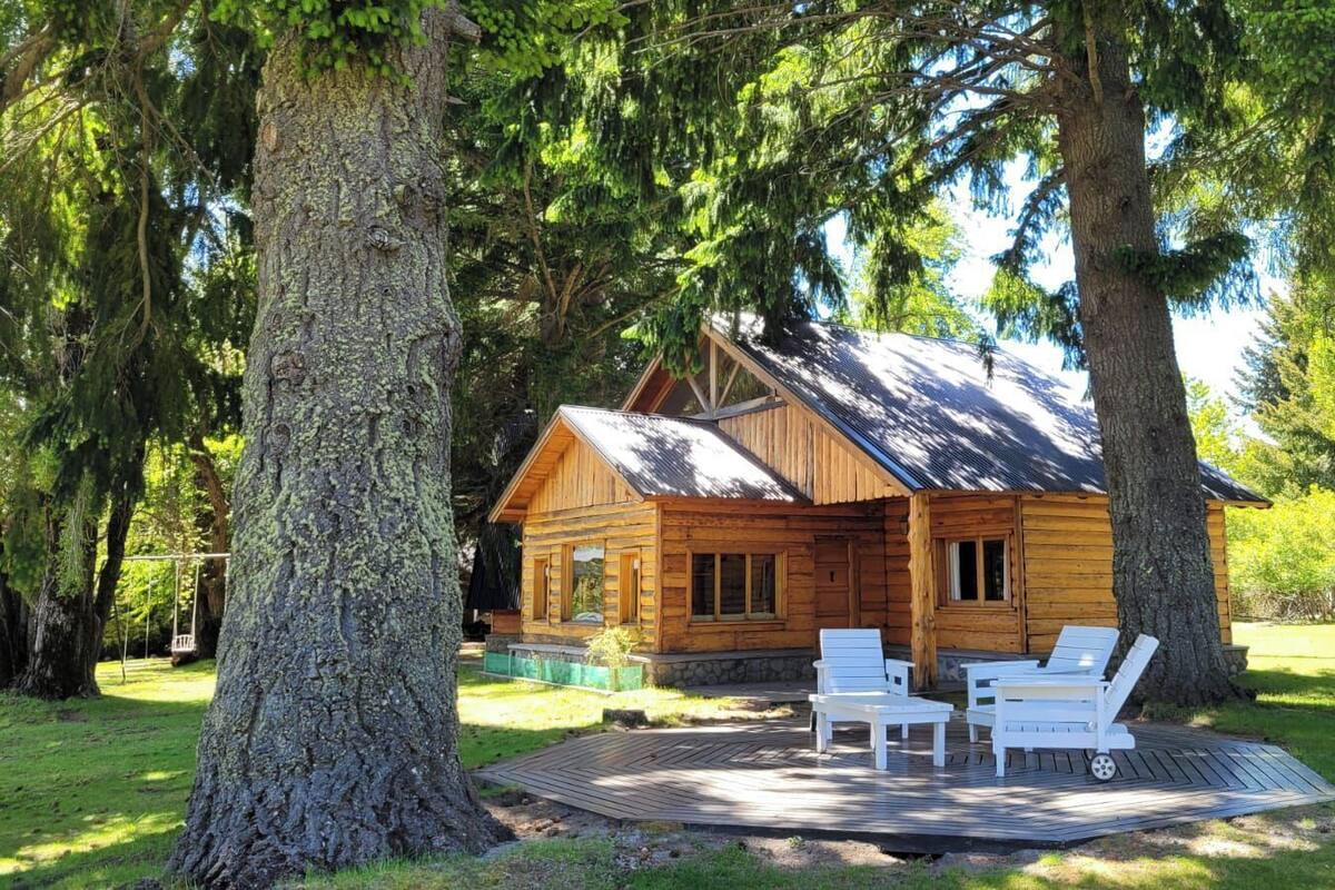 Een houten vakantiehuis met een terras en twee comfortabele stoelen.