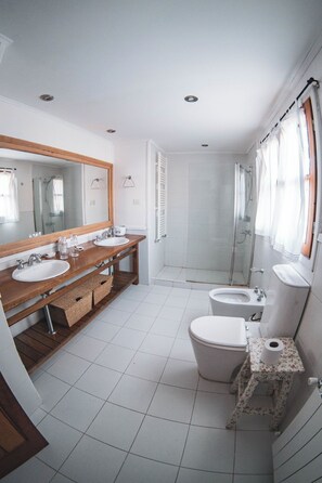 Een moderne badkamer met twee wasbakken, een toilet en een douche.