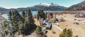 A mountainous landscape with a lake, several cabins, and a prominent building on a hill. - Hosteria Villarino (Nahuel Huapi National Park)