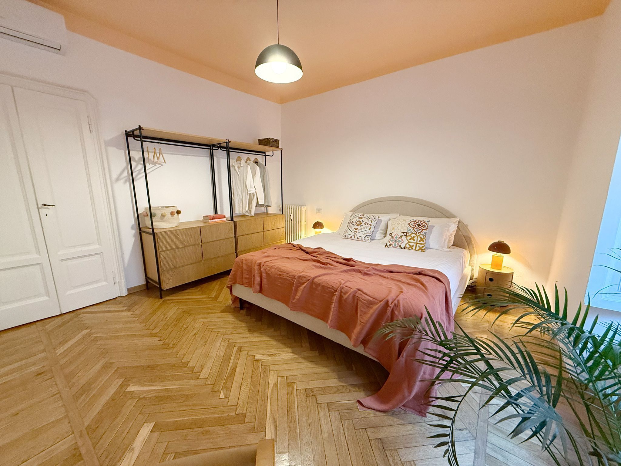 Una camera da letto con un letto, comodini, un armadio, uno specchio e un attaccapanni.