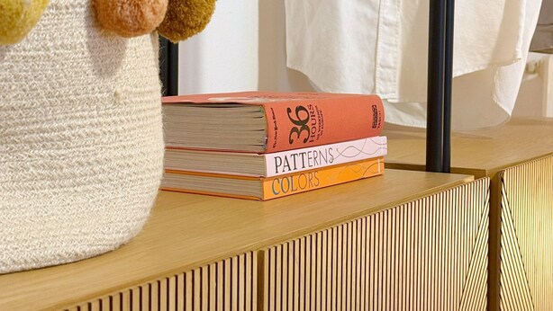 A wooden dresser with a textured fabric item and a stack of books titled 'Patterns & Colors'.