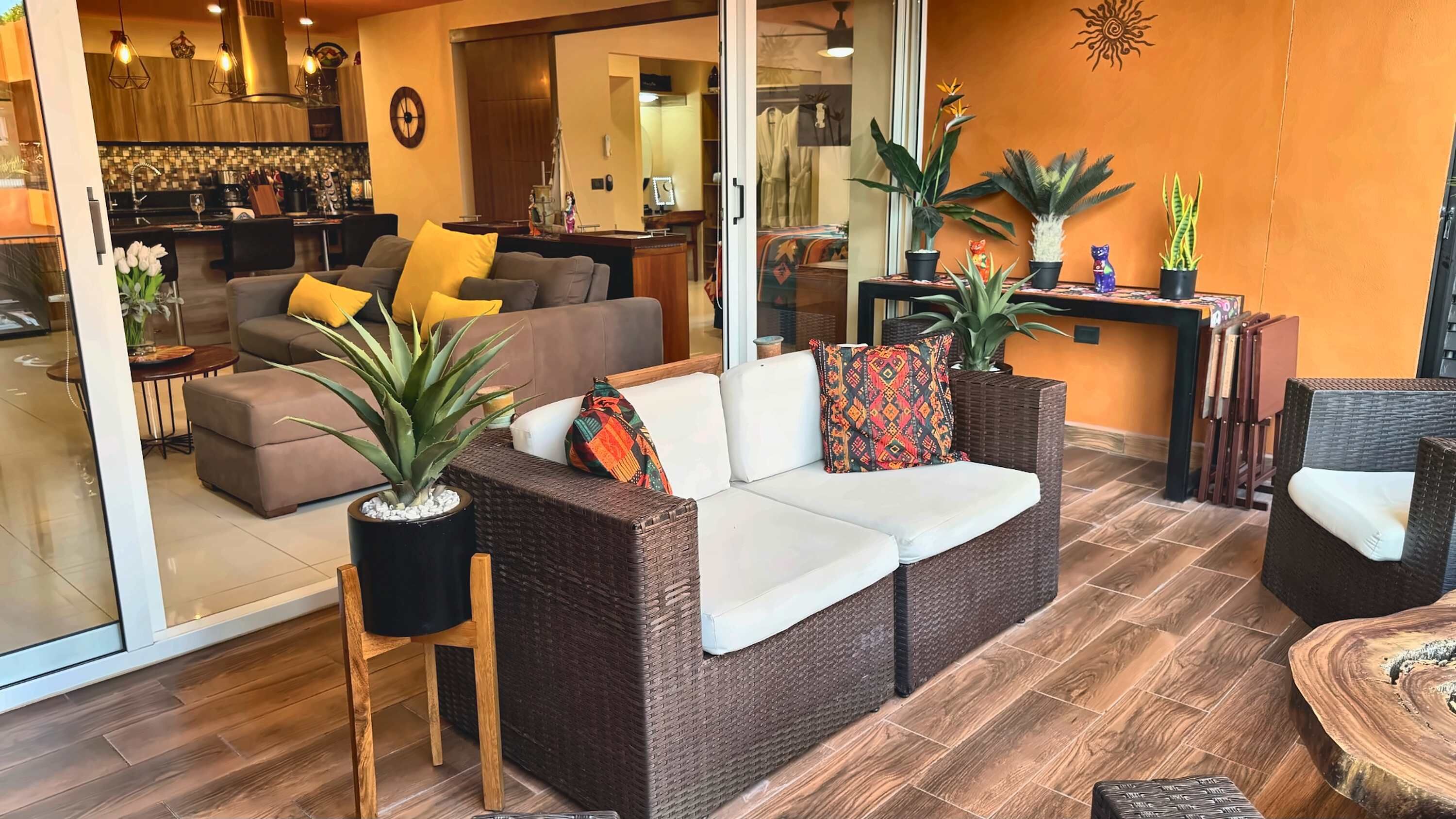 A modern living room with a sofa, chairs, and potted plants.