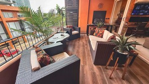 A balcony with wicker furniture, a dining table, and potted plants.