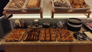 A buffet with various baked goods, including bread, pastries, and tarts. - Bacalhoeiros 125 Hotel (Lisbon)