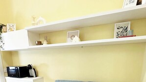 Ein Wohnzimmer mit einem blauen Sofa, zwei Kissen, einer weißen Decke und einem weißen Beistelltisch mit einer Mikrowelle.