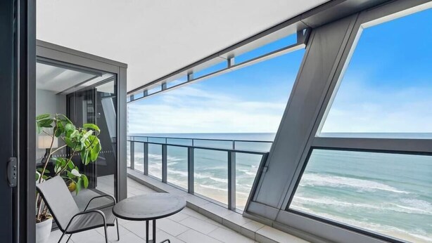 Een balkon met uitzicht op de oceaan, een bloempot en een klein tafeltje.