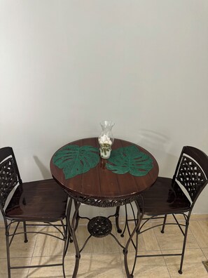 A dining table with two chairs, set with a vase and placemats.
