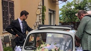 Um carro FIAT branco com um buquê de flores e uma fita branca na frente.