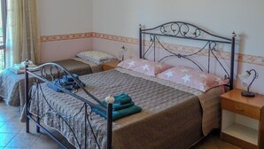 Quarto com cama, mesa de cabeceira, luminária e cortinas.