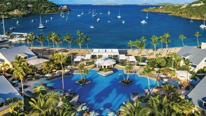 Un resort con múltiples piscinas, una zona de playa y un puerto deportivo con barcos.
