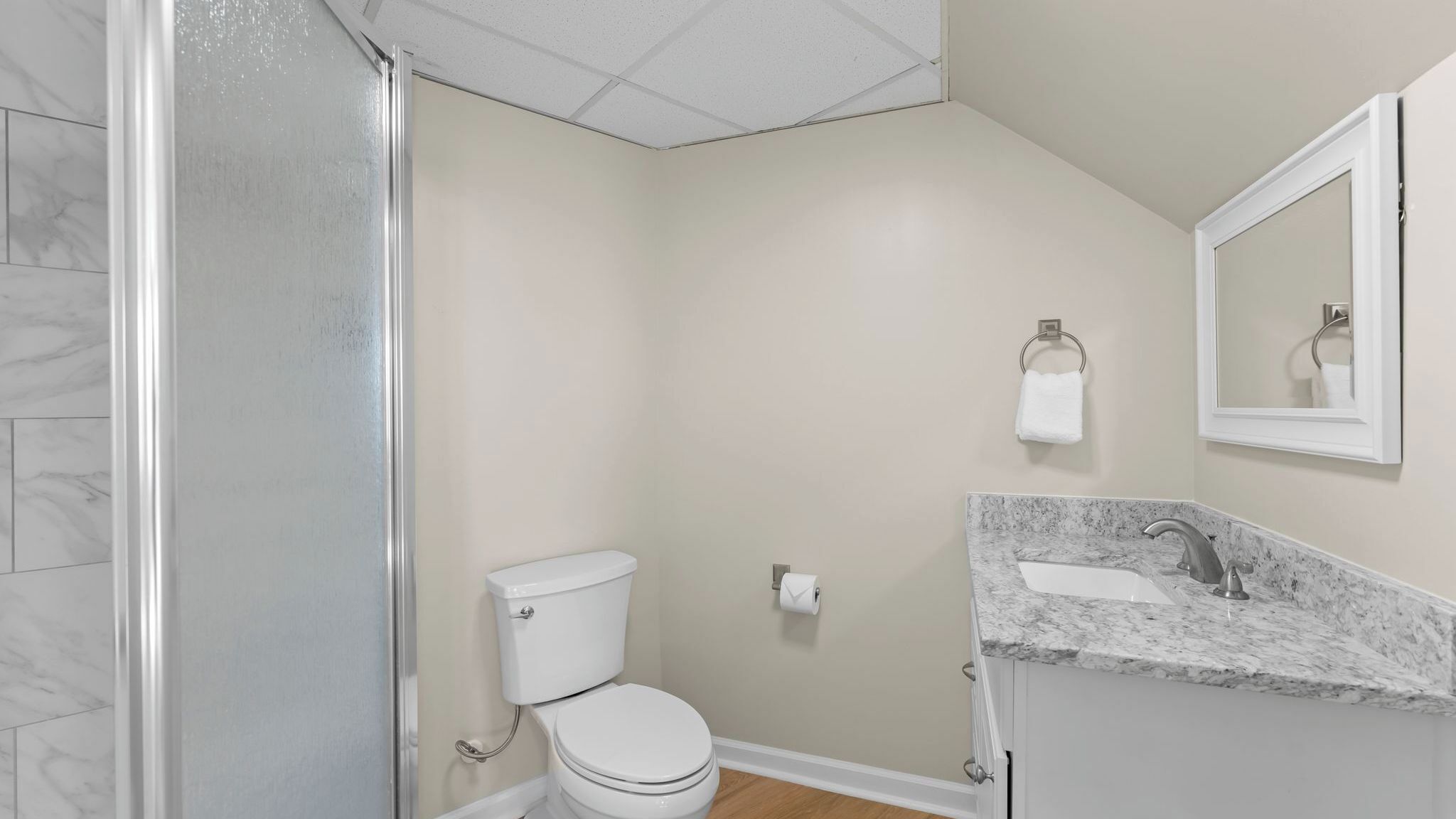 A bathroom with a shower, toilet, sink, and mirror.