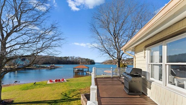A deck with a grill, overlooking a lake with a dock and a gazebo. - Pleasant Cove Waterfront Getaway With Fire Pit, Deck, and Lake Views (Mooresville)