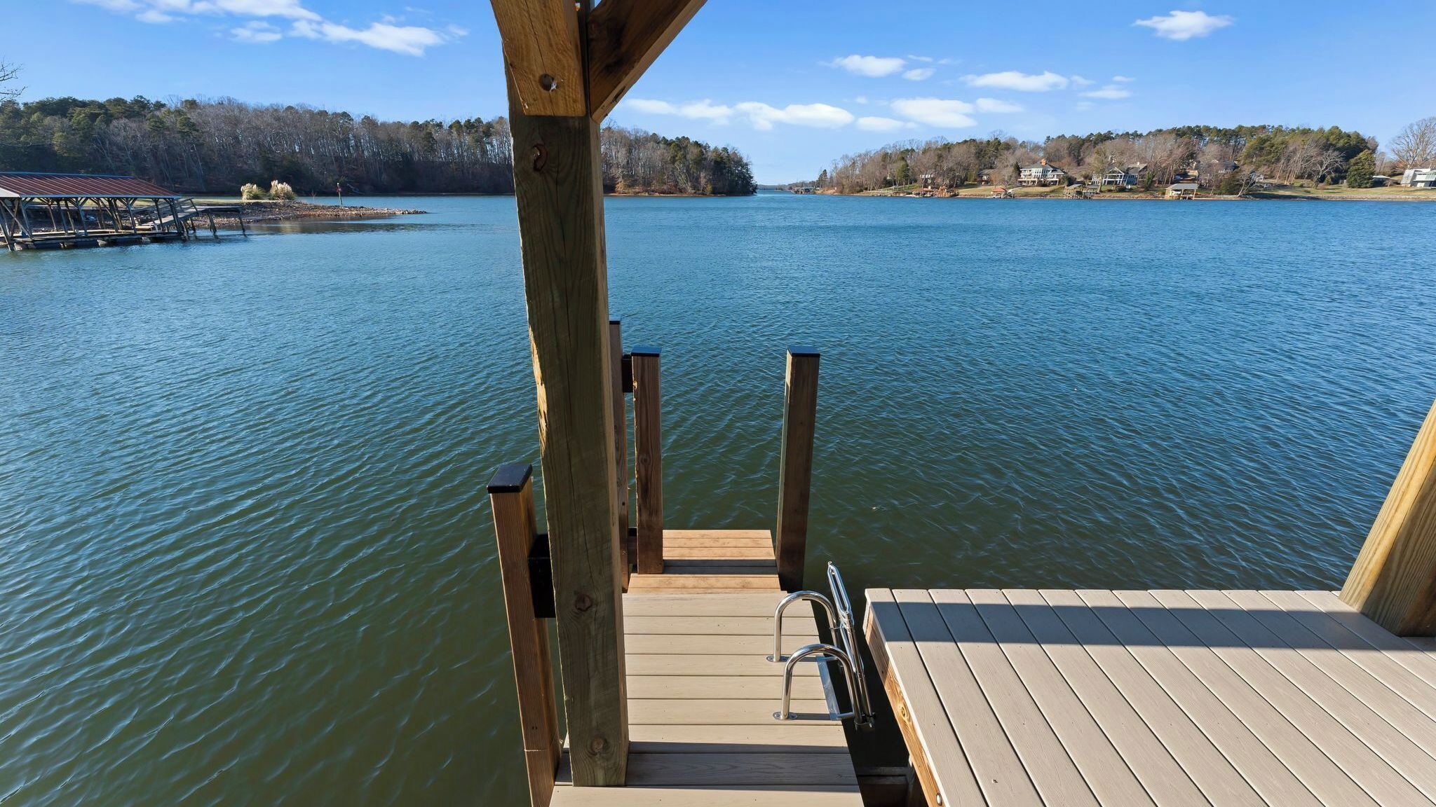 A wooden dock extending into a calm lake with a clear view of the surrounding landscape.
