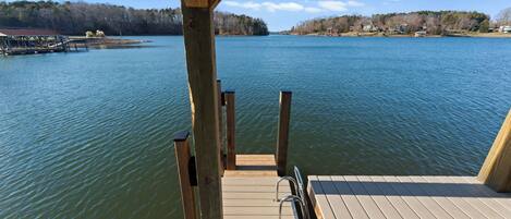 A wooden dock extending into a calm lake with a clear view of the surrounding landscape.