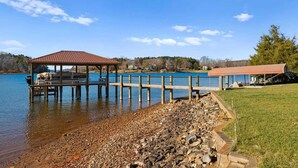 A lakeside dock with a covered pavilion and a building with a red roof. - Pleasant Cove Waterfront Getaway With Fire Pit, Deck, and Lake Views (Mooresville)