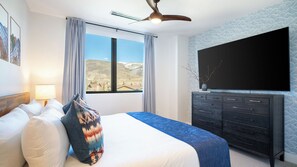A bedroom with a bed, a dresser, a ceiling fan, a TV, and a window with a view of a landscape. - Alpine Oasis at Frontgate by Avantstay Luxe 3bdr Near Vail w/ Views Gym, Pool, Game Room (Avon)
