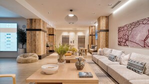 A modern interior with a wooden accent wall, a sofa, a coffee table, and a TV screen displaying a weather forecast. - Alpine Oasis at Frontgate by Avantstay Luxe 3bdr Near Vail w/ Views Gym, Pool, Game Room (Avon)