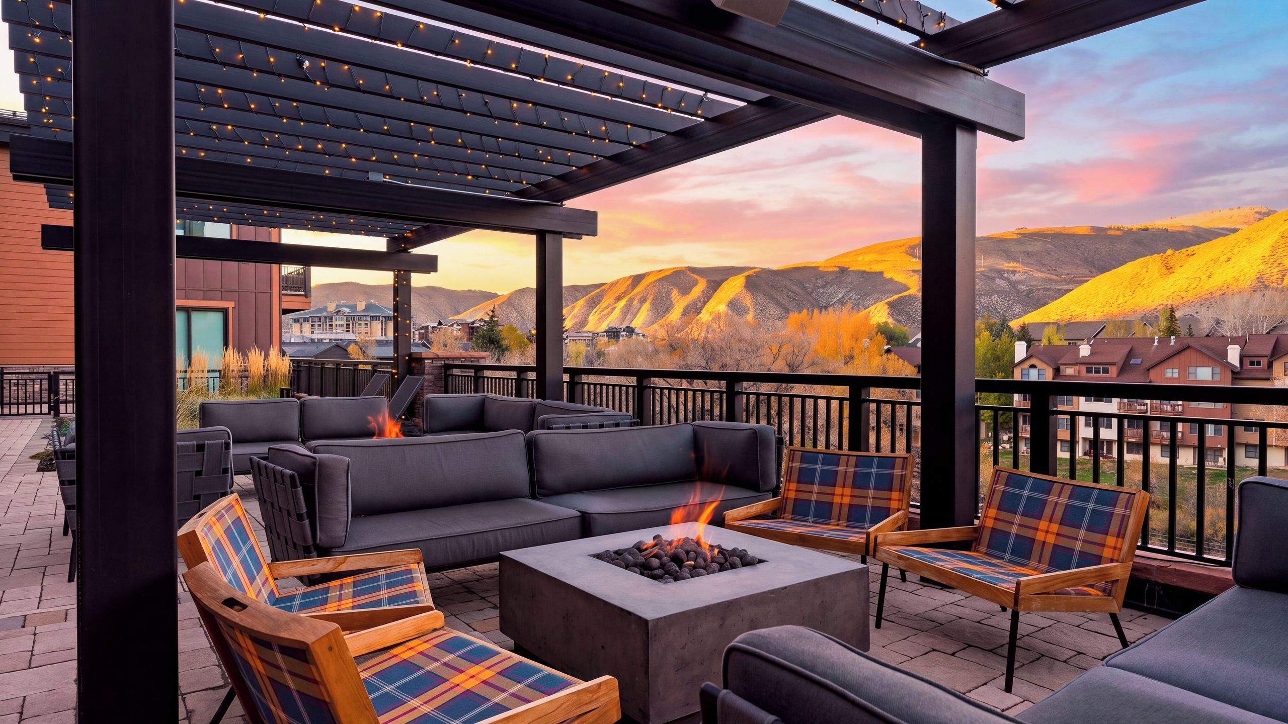 Une terrasse extérieure dotée d’un foyer, de sièges et offrant une vue sur un paysage montagneux.